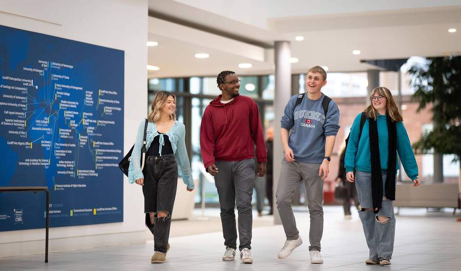 Four students walking alongside each other in the Cardiff School of Management.