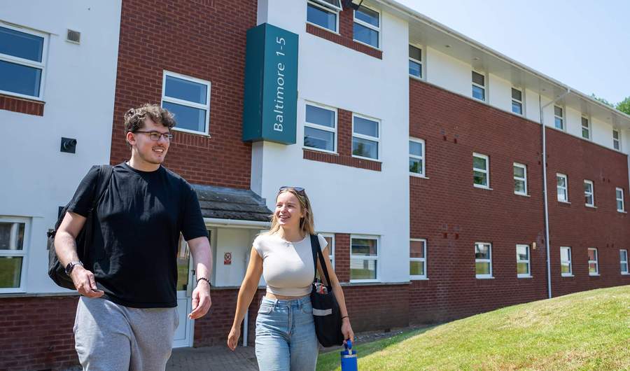 Two people walking together outside an accommodation block at Cardiff Met.