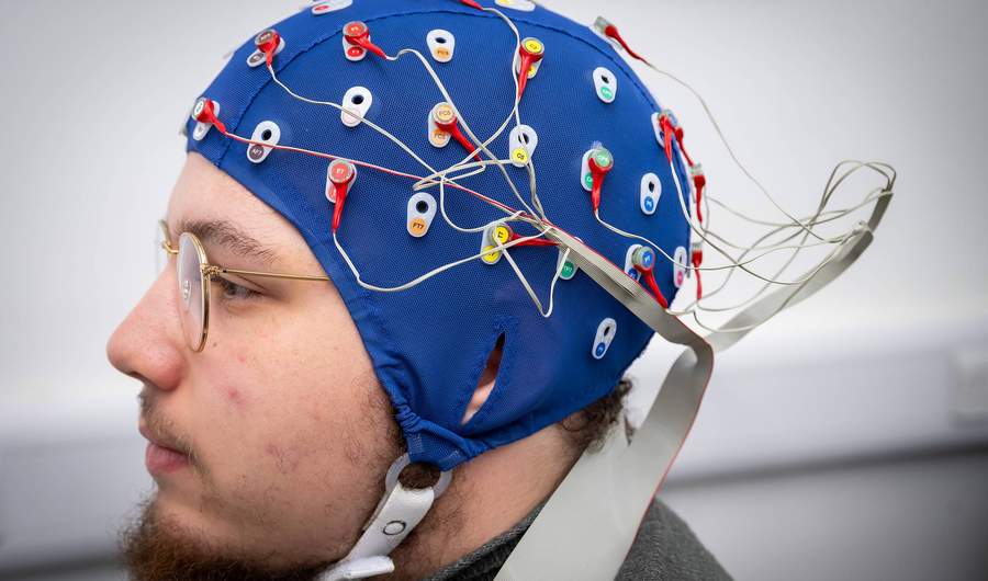A close-up of a person wearing a cap fitted with electrical sensors.
