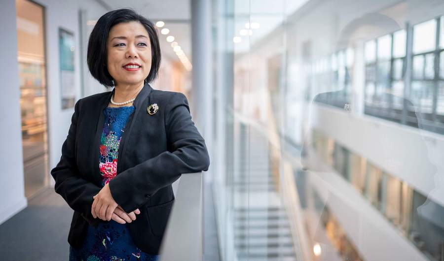 A person leans against a railing in a brightly-lit atrium space.