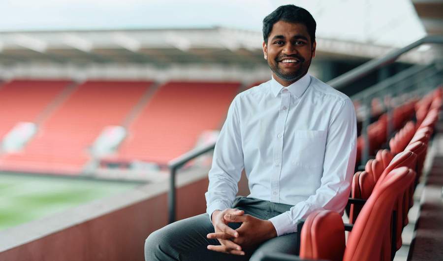 A person sits in the empty stands of a football stadium.