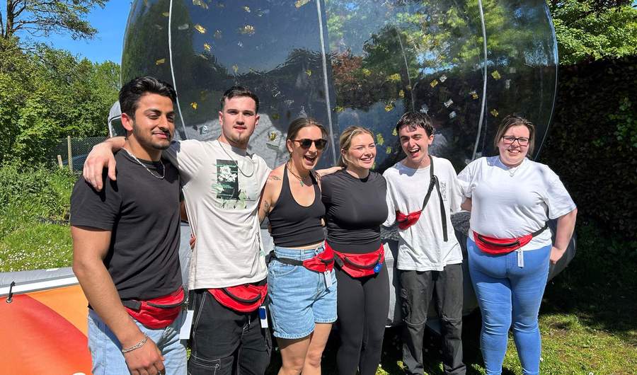 A group of people stand in a row, arm in arm.