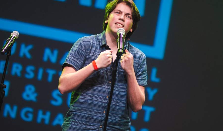 A person stands in front of a microphone on a stage.
