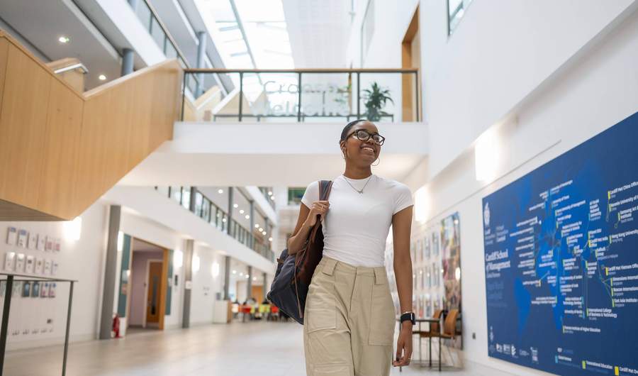 A student walks through the bottom floor of the Cardiff School of Management