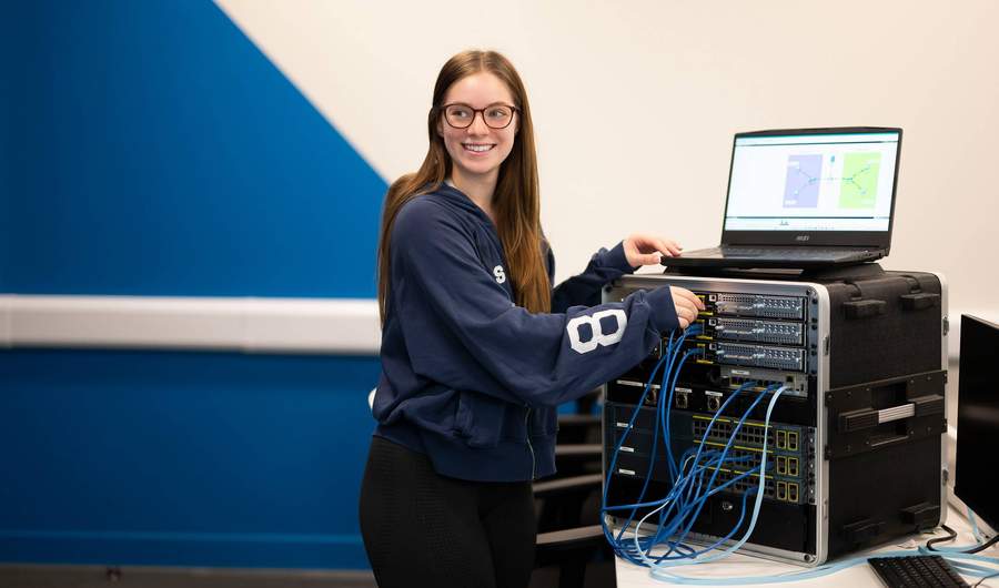 A person plugs cables into computer network equipment.
