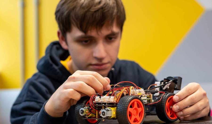 A person assembling a wheeled robot.