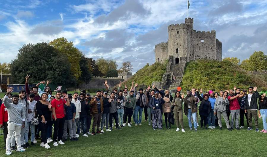 A large group of people line up in front of a castle-like structure.