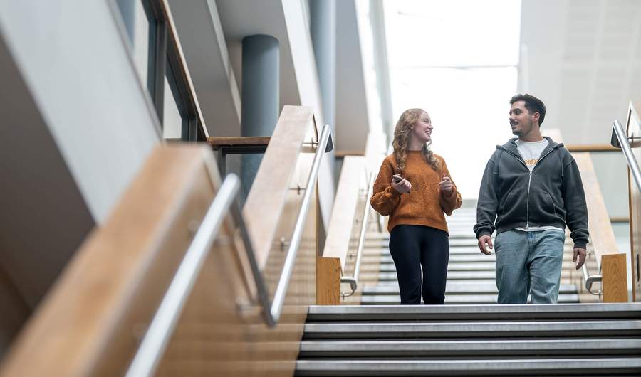 Two people walking down a staircase in a large, open space.