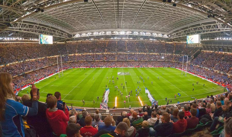 A large stadium filled with spectators watching a rugby match in progress.