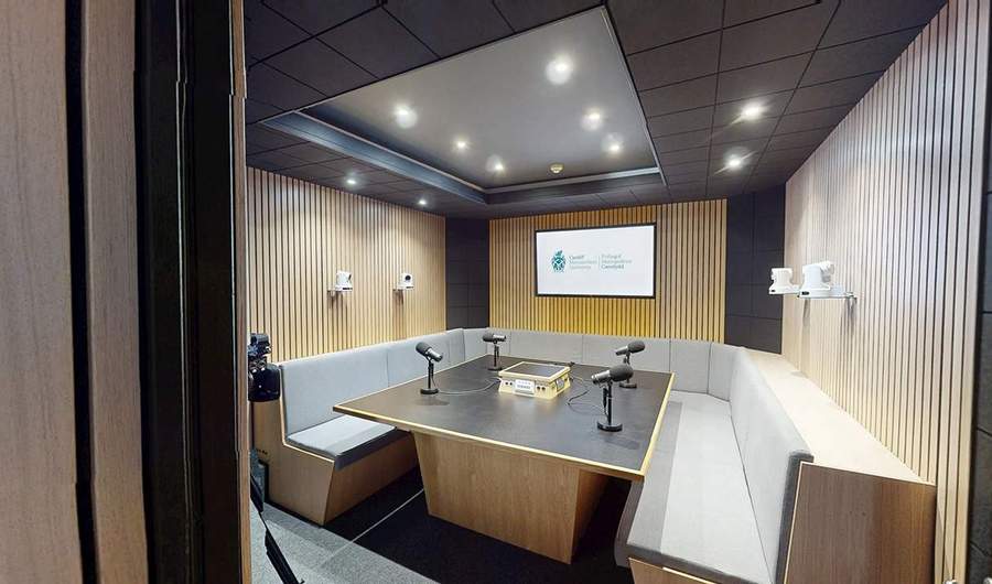 A podcast recording studio with curved seating, microphones and video cameras.