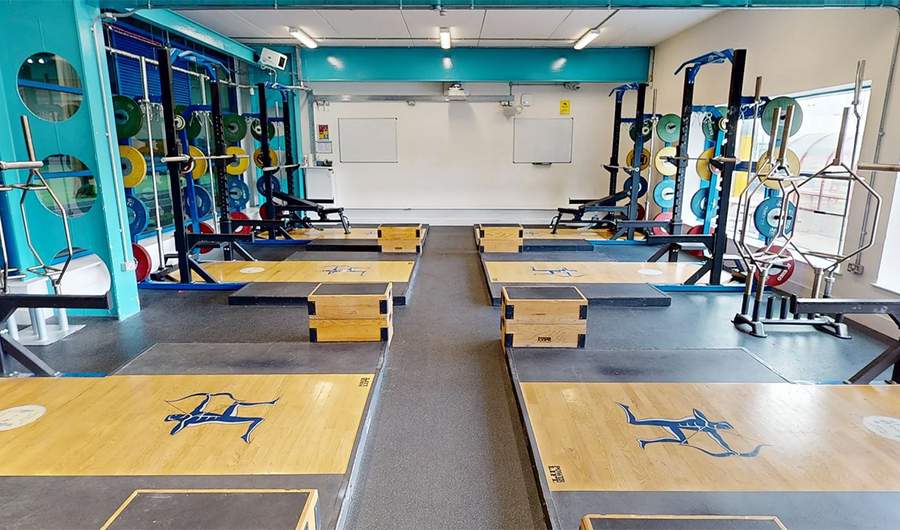 A gym with multiple lifting platforms, squat racks, and weights.