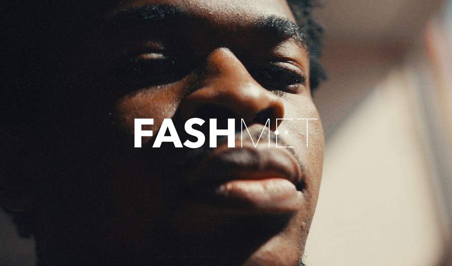 A young man looks into the camera with the text 'FashMet' in front of his face