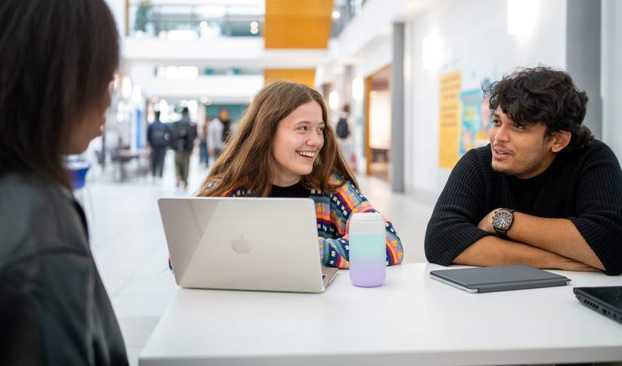Three students engage in discussion inside the Cardiff School of Management