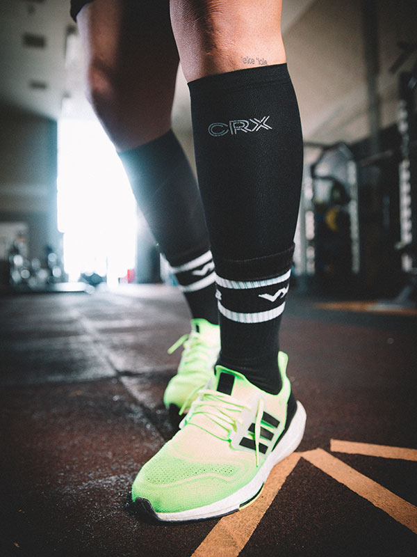 Student athlete legs and feet, wearing CRX branded socks and green exercise trainers