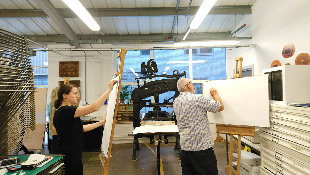 In a vibrant studio, a man and woman focus on creating a painting together, with art supplies scattered around them.