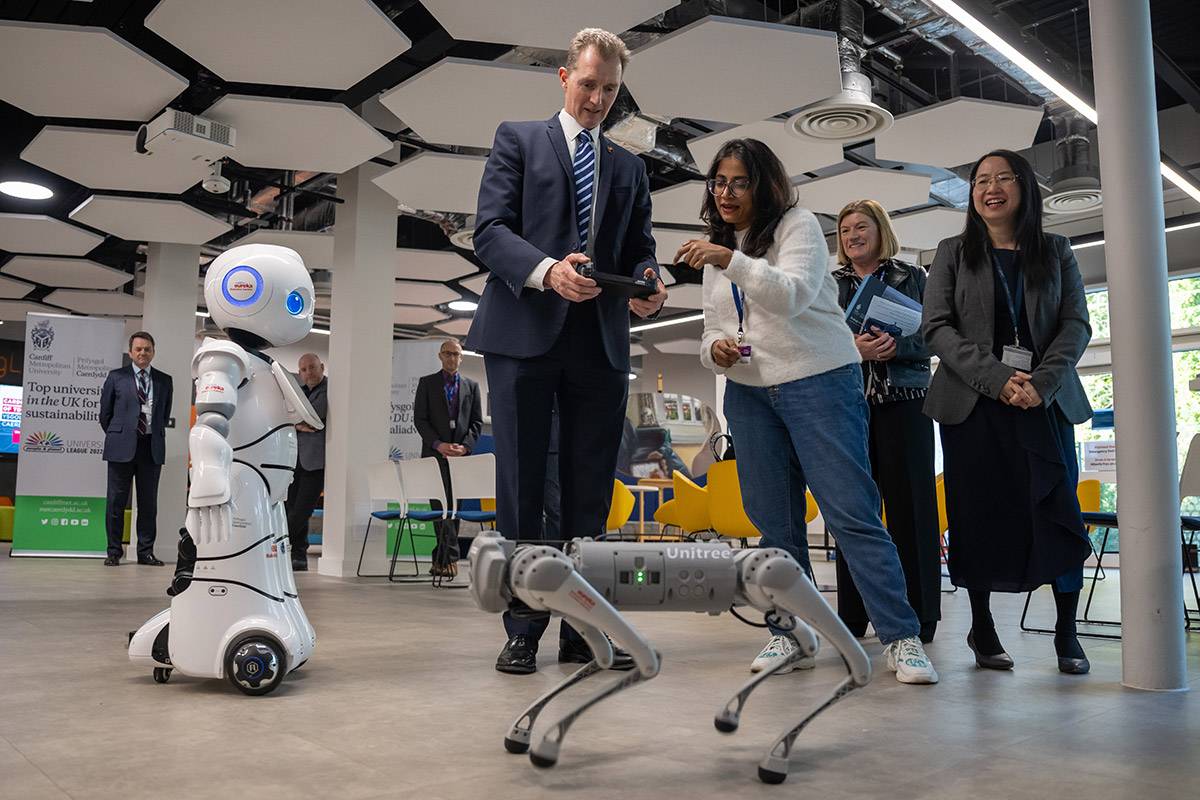 David TC Davies uses remote control to guide a robot with guidance from Cardiff Met student