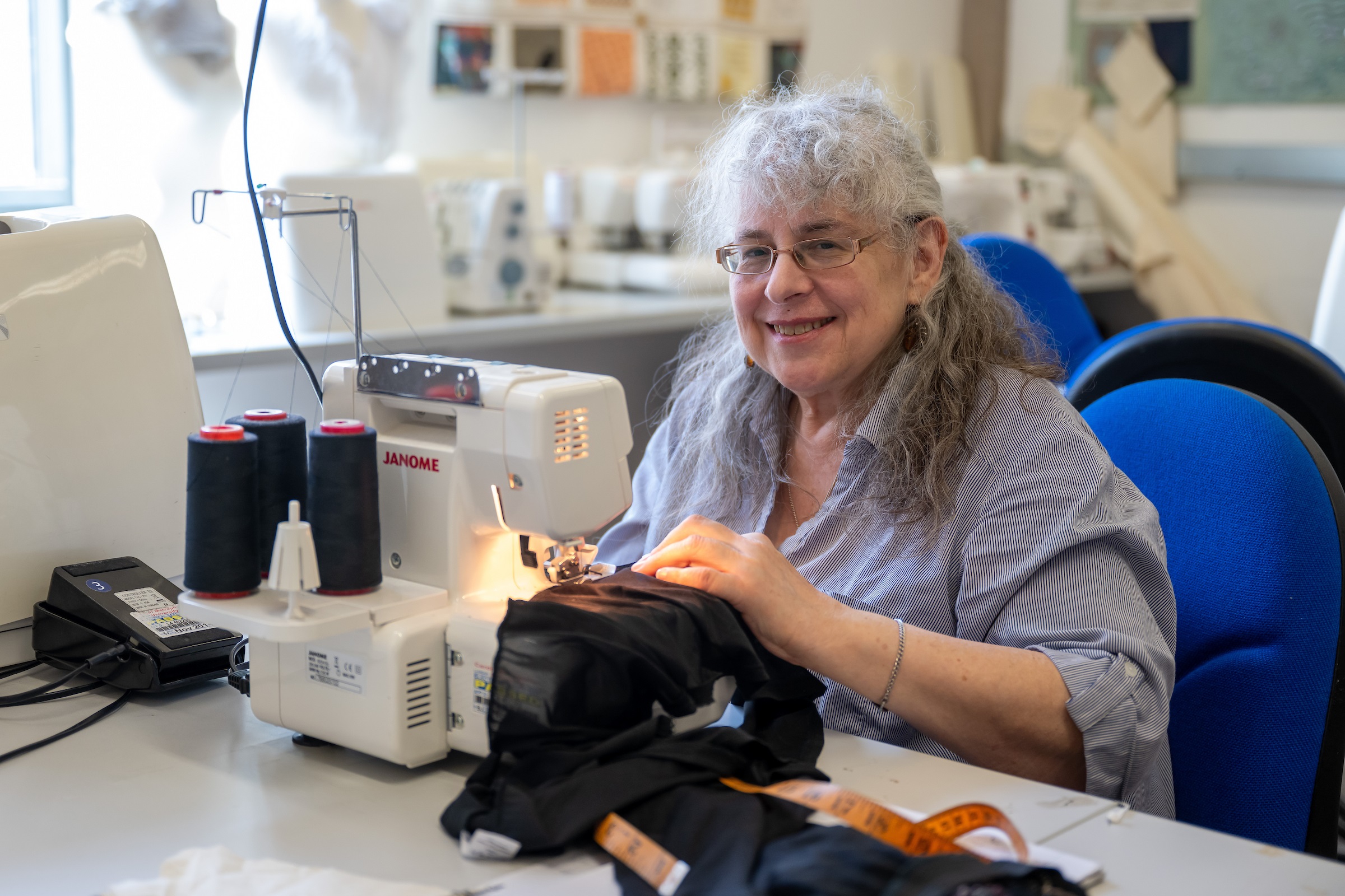An elderly woman works at a sewing machine