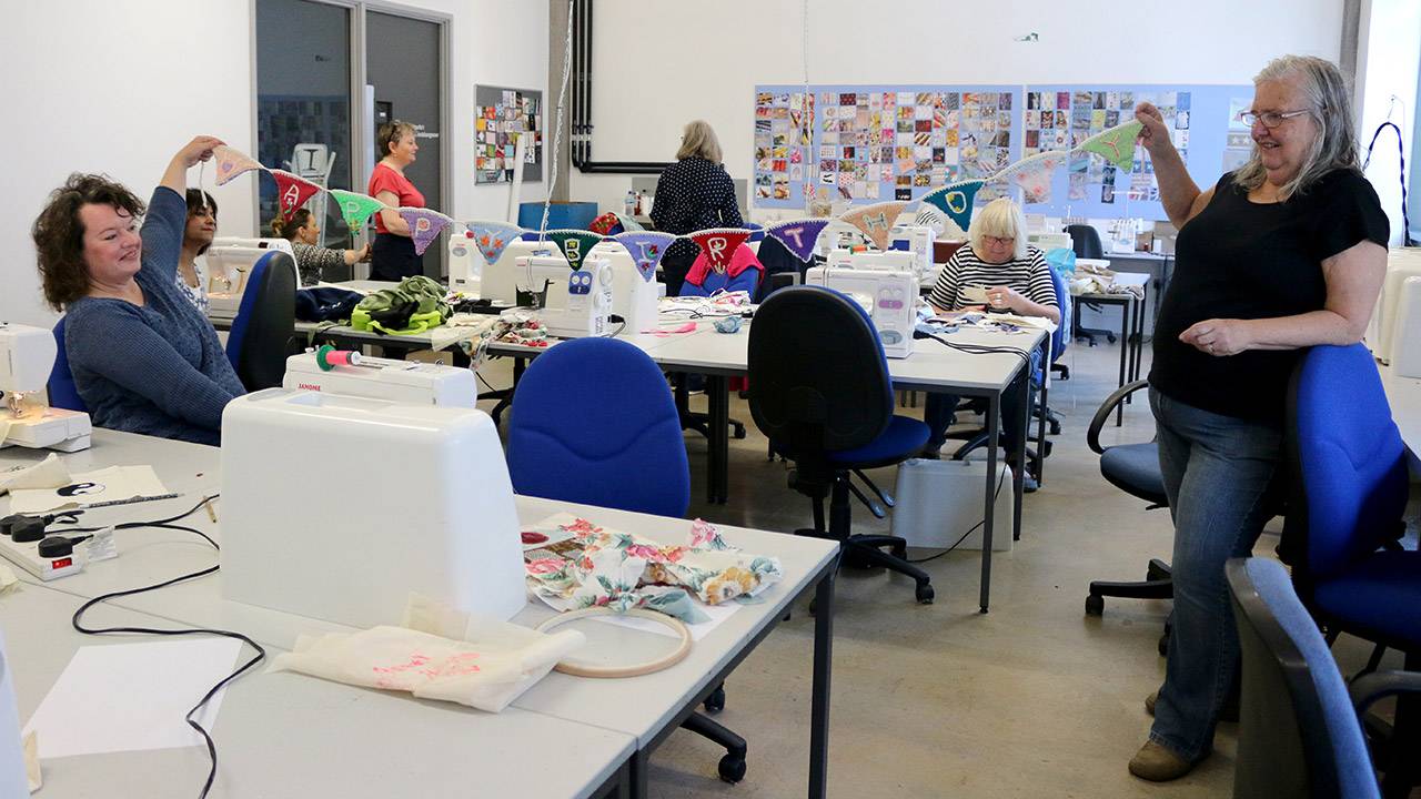 Summer School participants show a knitted 'Happy Birthday' bunting