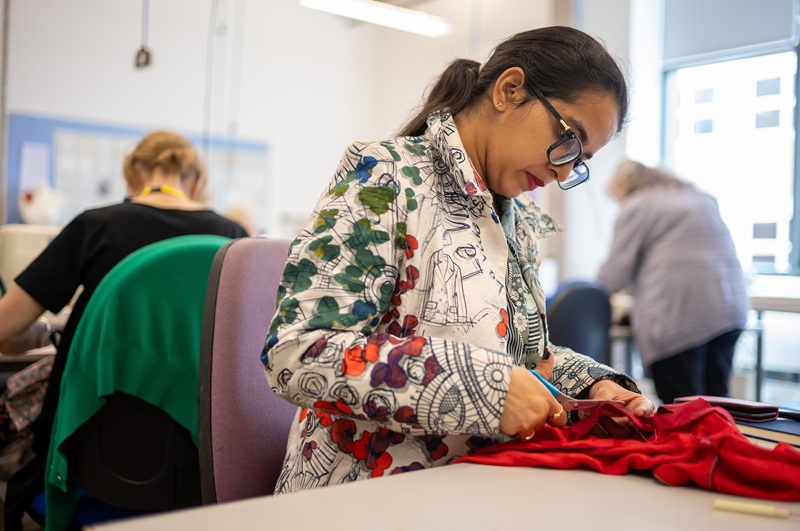 Adult learner cuts fabric with scissors