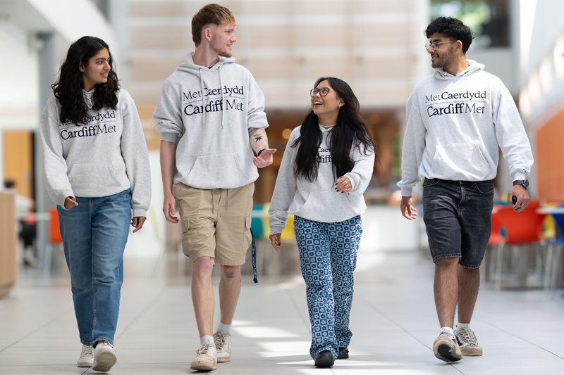 Four Cardiff Met student ambassadors walking together in matching branded hoodies