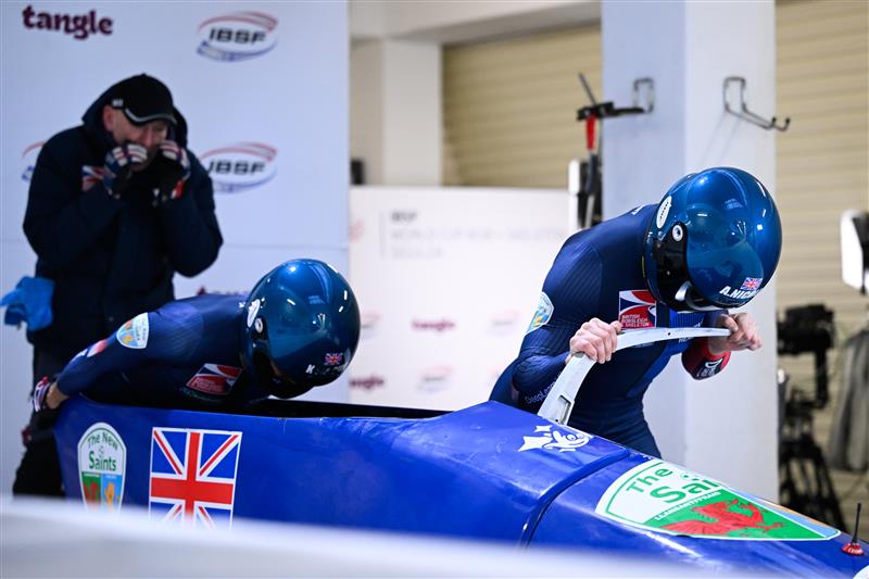 Two team GB athletes prepare to launch their bobsleigh down the track during competition