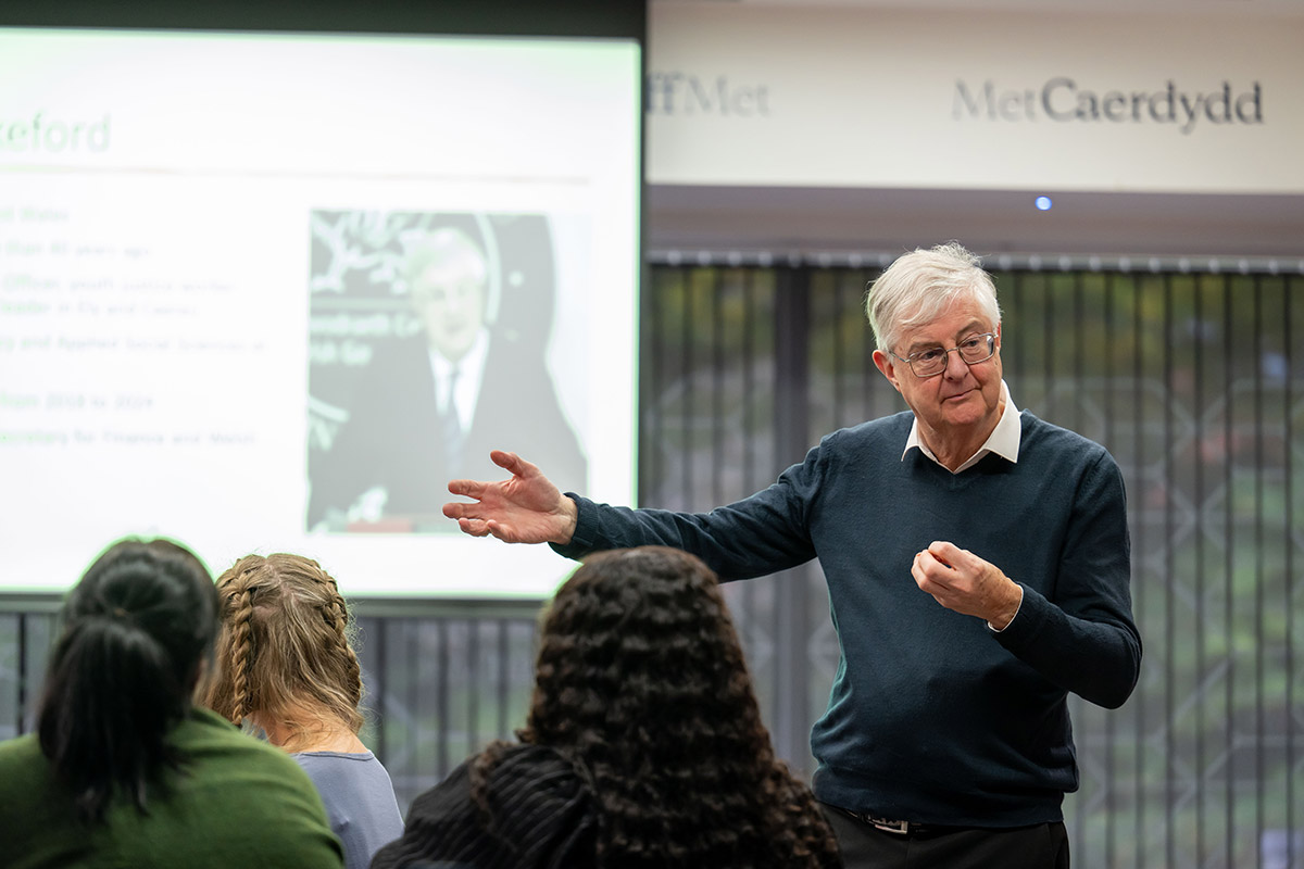 A senior man addressing a group, sharing insights during a formal presentation.