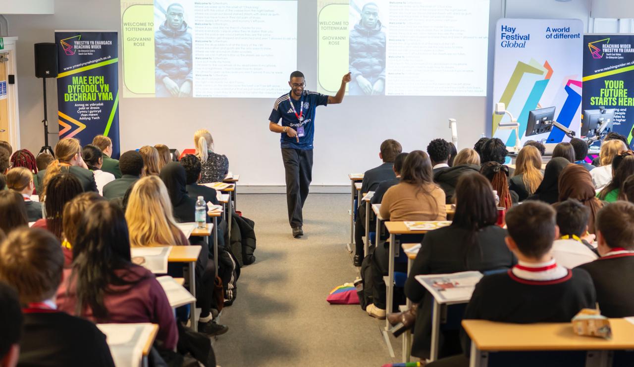 Man points as they stand between rows of desks while giving a lecture