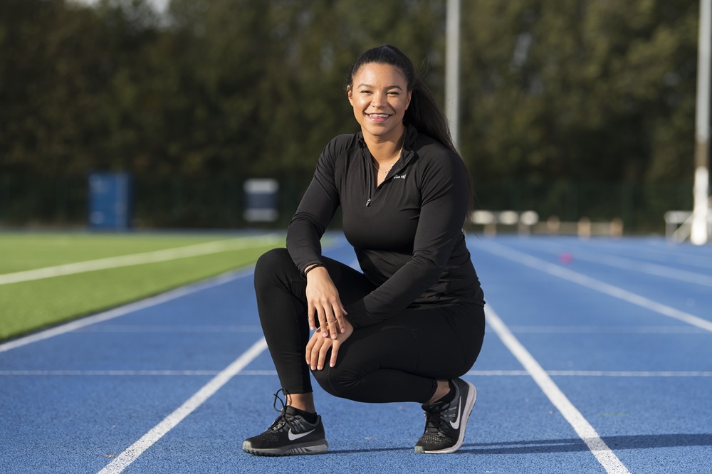 Cardiff Met student in black sportswear crouches on running track