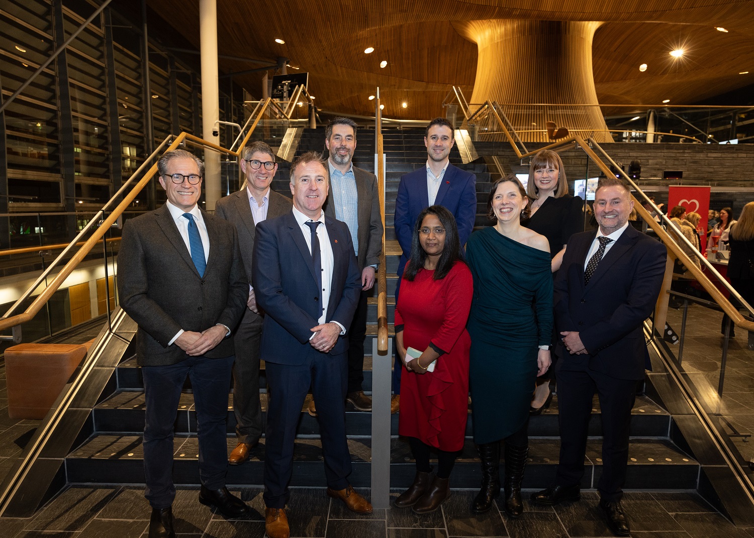 The National Cardiovascular Research Network research team sand for a photograph at the bottom of a staircase in the Senedd