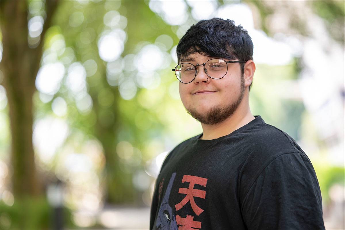 Headshot of Alex Jones in front of greenery