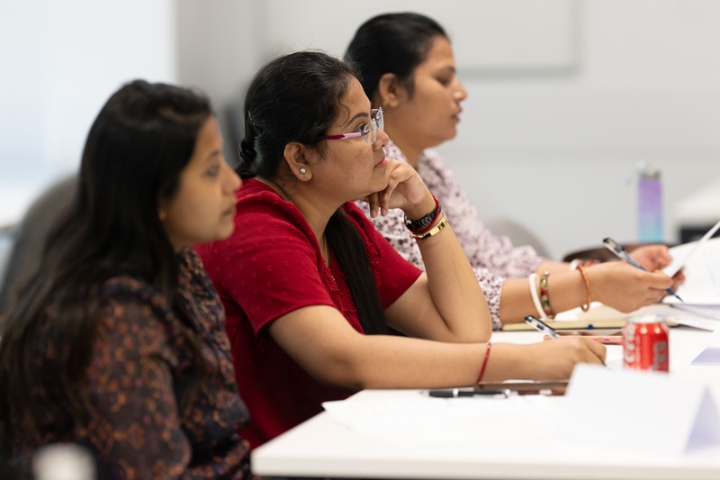 Three adult learners sit at a table during a lesson