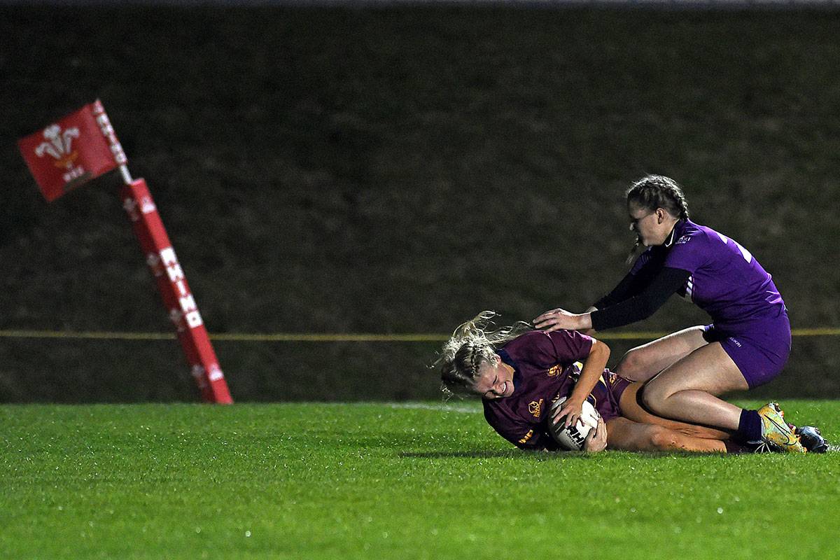 Two women compete for the rugby ball during a game