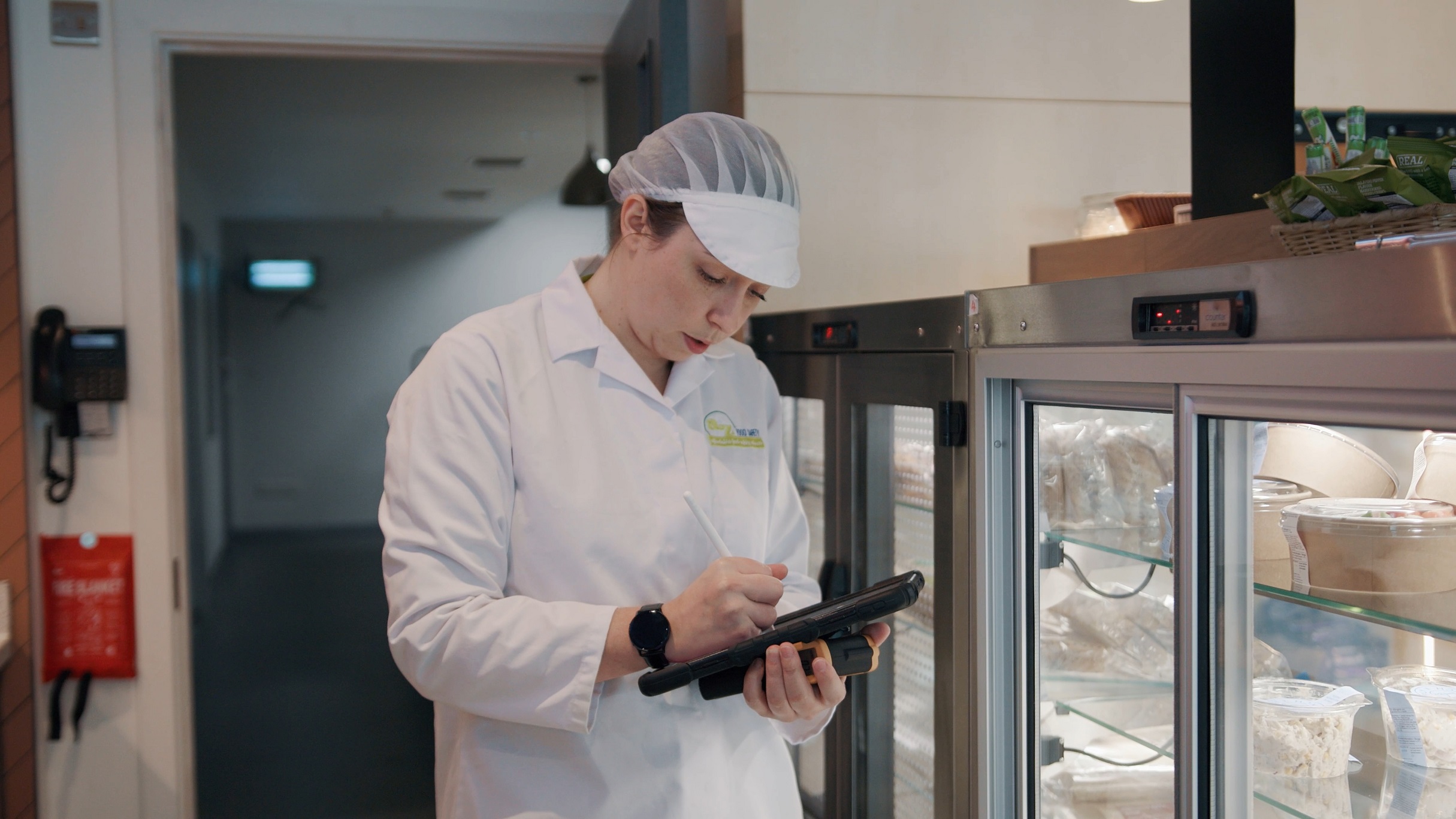 Environmental Health student in white lab coat writes on digital notepad