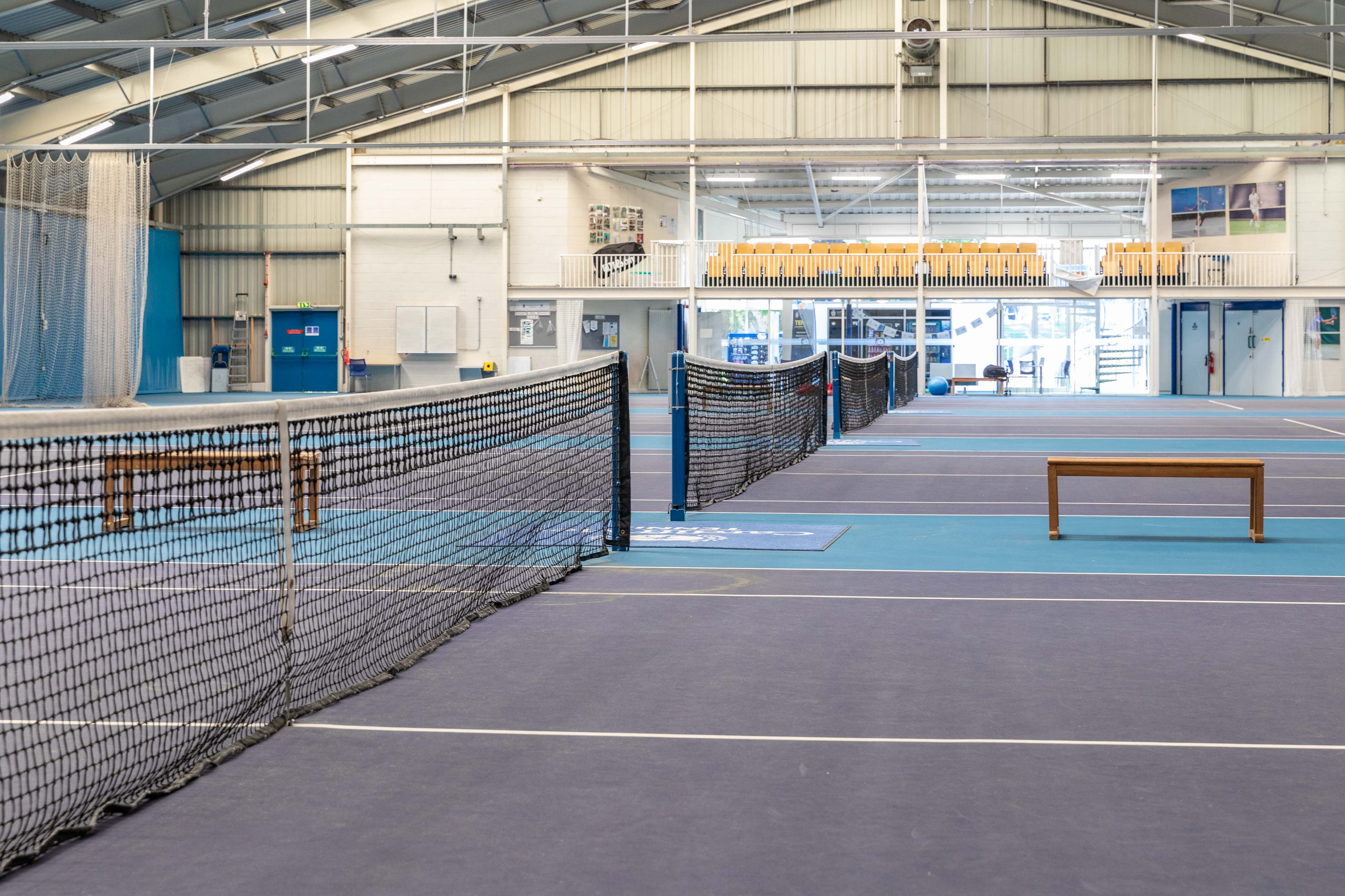 A view across several tennis courts in a large inside sports centre
