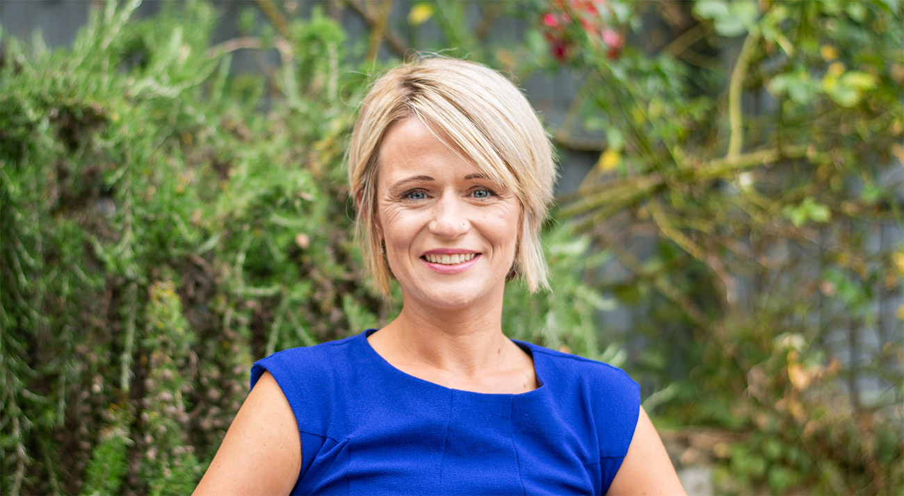 A woman wearing a blue dress is seated on a bench, enjoying a moment of relaxation outdoors.
