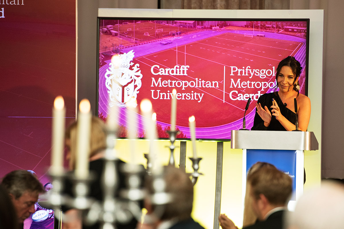 A woman delivering a speech at a formal dinner event, engaging the audience with her presentation.