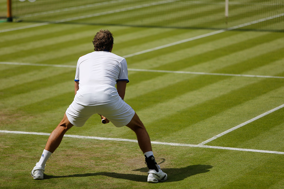 A man is positioned on a tennis court, ready to hit a tennis ball, showcasing athletic posture and concentration.